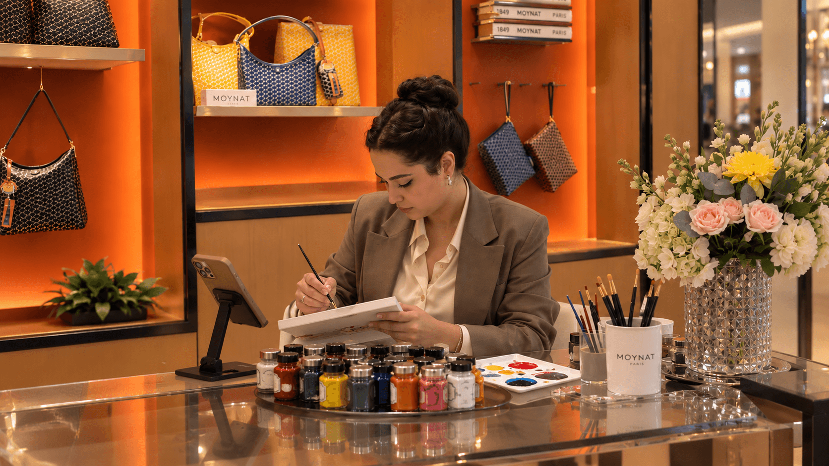 Lisamon painting at her studio table, surrounded by paints and brushes